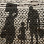 Refugees behind a fence Refugees behind a fence