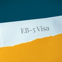 EB-5 Visa. Hand opens envelope and takes out documents. Post letter labeled with text